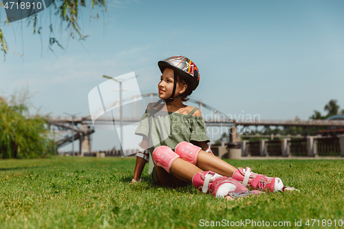 Image of Teenage girl in a helmet learns to ride on roller skates outdoors