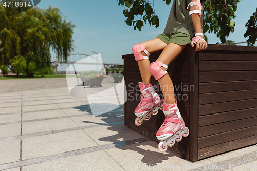 Image of Teenage girl in a helmet learns to ride on roller skates outdoors