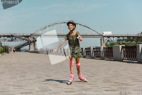 Image of Teenage girl in a helmet learns to ride on roller skates outdoors