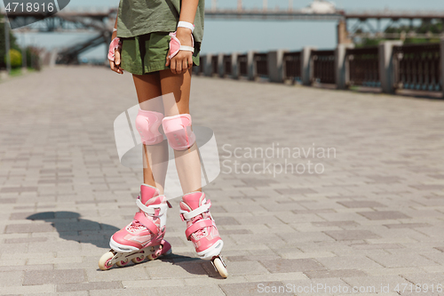 Image of Teenage girl in a helmet learns to ride on roller skates outdoors