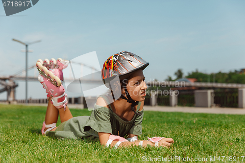 Image of Teenage girl in a helmet learns to ride on roller skates outdoors