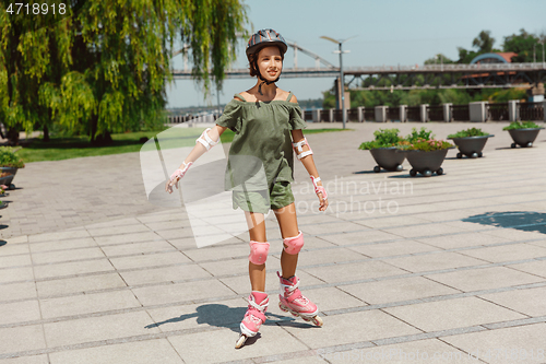 Image of Teenage girl in a helmet learns to ride on roller skates outdoors