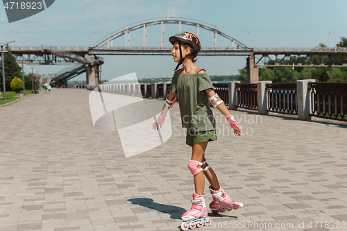 Image of Teenage girl in a helmet learns to ride on roller skates outdoors