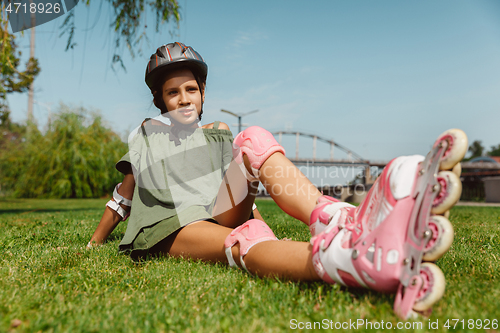 Image of Teenage girl in a helmet learns to ride on roller skates outdoors