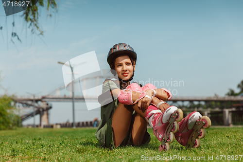 Image of Teenage girl in a helmet learns to ride on roller skates outdoors