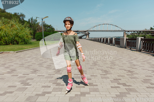 Image of Teenage girl in a helmet learns to ride on roller skates outdoors