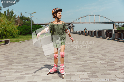 Image of Teenage girl in a helmet learns to ride on roller skates outdoors