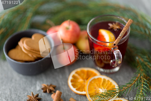 Image of glass of hot mulled wine, cookies, apples and fir