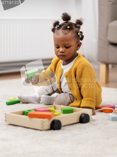 Image of african baby girl playing with toy blocks at home