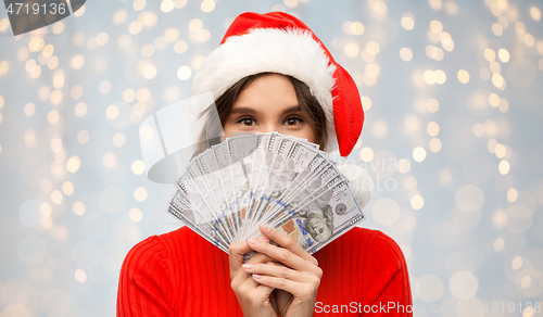 Image of happy woman in santa hat with money on christmas