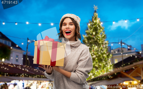 Image of woman in hat holding gift box at christmas market