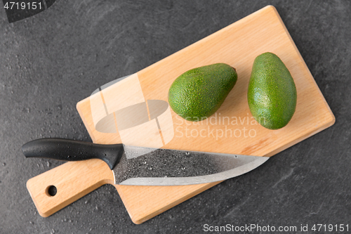 Image of two avocados and kitchen knife on cutting board