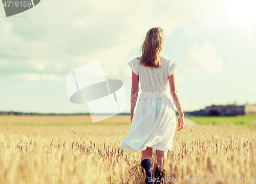 Image of young woman in white dress walking along on field