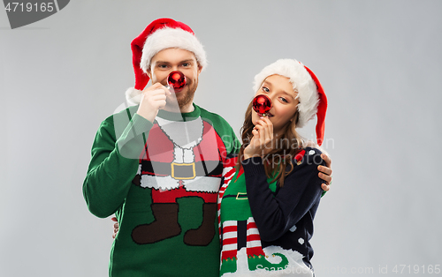 Image of happy couple in christmas sweaters and santa hats