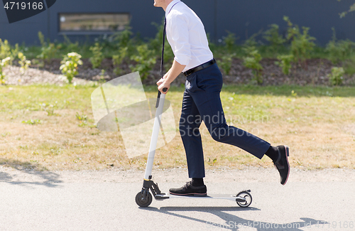 Image of young businessman riding electric scooter outdoors