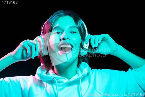 Image of woman in headphones listening to music in neon
