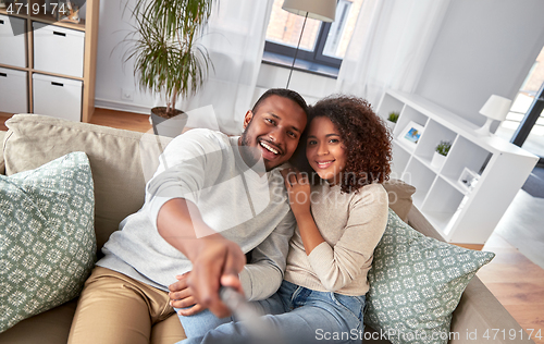 Image of couple taking picture by selfie stick at home