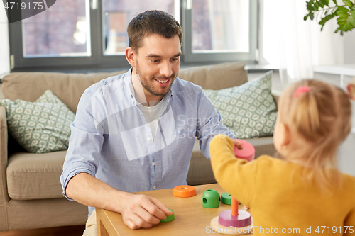 Image of father playing with little baby daughter at home