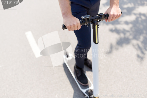 Image of young businessman riding electric scooter outdoors