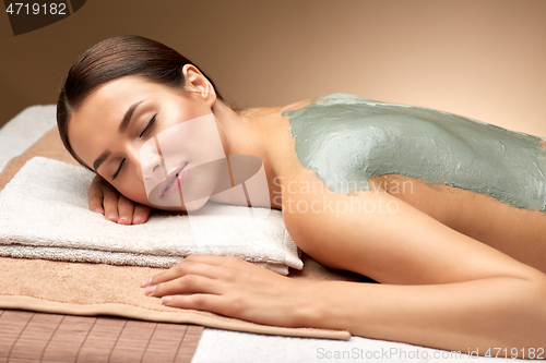 Image of woman with blue clay mask on back in spa