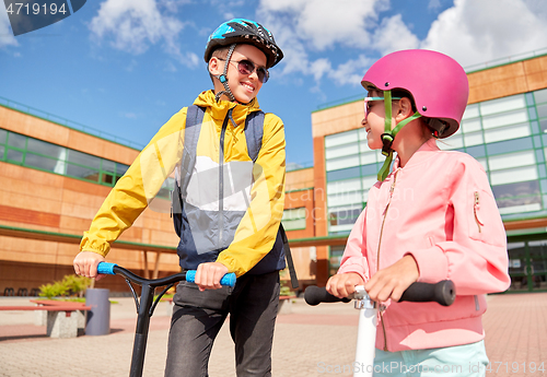 Image of happy school children with backpacks and scooters