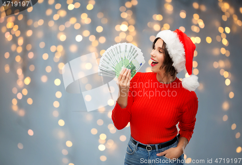 Image of happy woman in santa hat with money on christmas