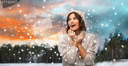 Image of woman in hat and sweater over winter forest