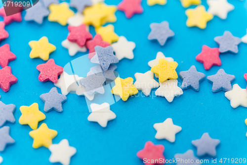 Image of star shaped pastry sprinkles on blue background