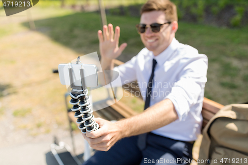 Image of businessman recording video blog by smartphone