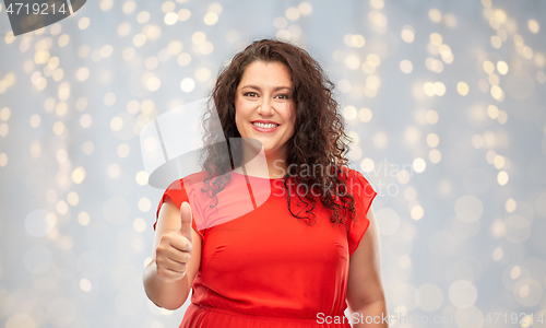 Image of happy woman showing thumbs up over lights