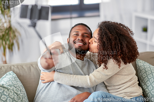 Image of couple taking picture by selfie stick at home