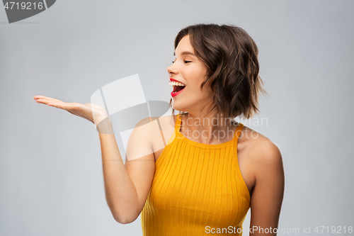 Image of happy young woman holding something on empty hand