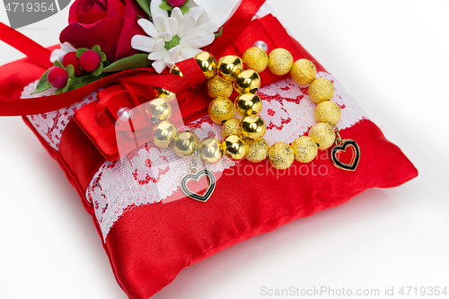 Image of pillow with golden beads bracelet rings 