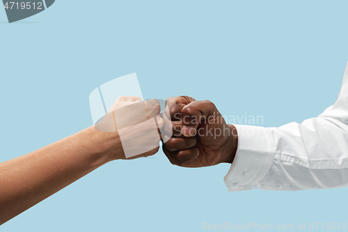 Image of Two male hands competion in arm wrestling isolated on blue studio background