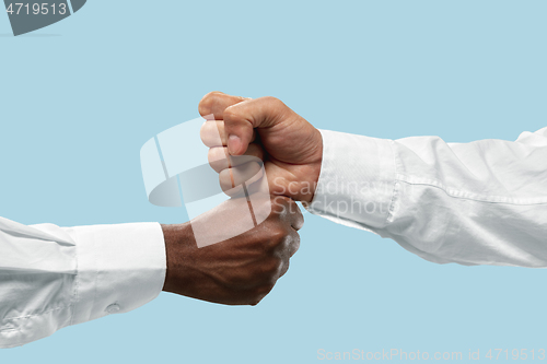 Image of Two male hands competion in arm wrestling isolated on blue studio background