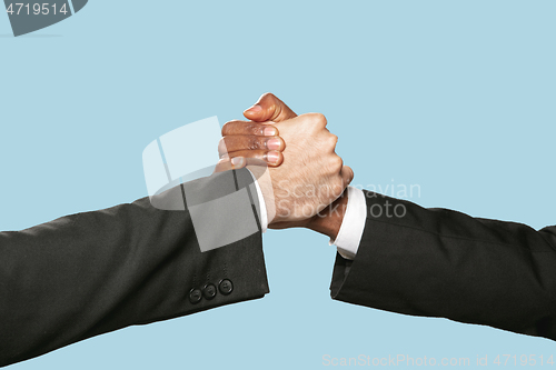 Image of Two male hands shaking isolated on blue studio background