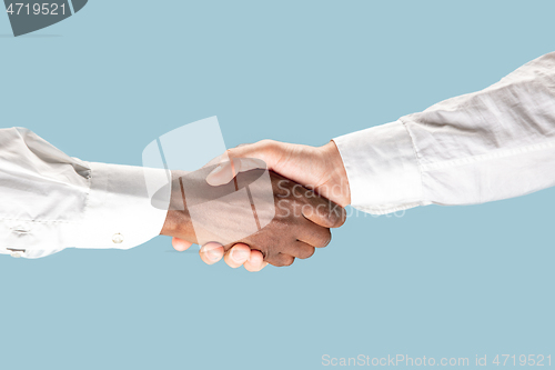 Image of Two male hands shaking isolated on blue studio background