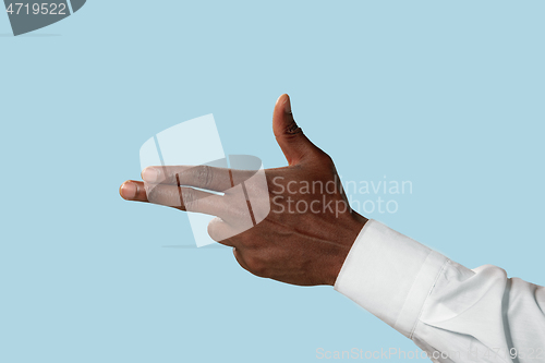 Image of Male hand demonstrating a gesture of gun isolated on blue background