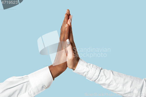 Image of Two male hands shaking isolated on blue studio background