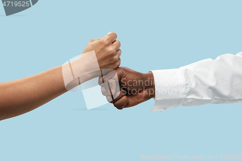 Image of Two male hands competion in arm wrestling isolated on blue studio background