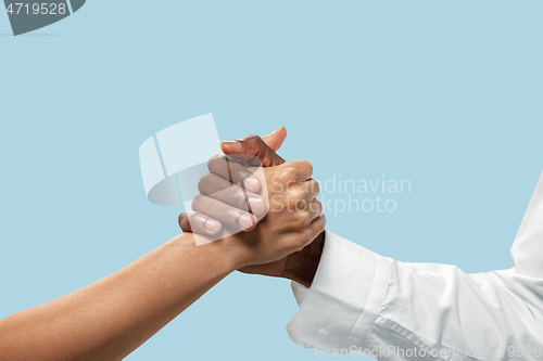 Image of Two male hands competion in arm wrestling isolated on blue studio background