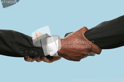 Image of Two male hands shaking isolated on blue studio background