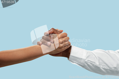 Image of Two male hands competion in arm wrestling isolated on blue studio background