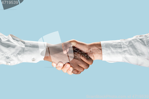 Image of Two male hands shaking isolated on blue studio background