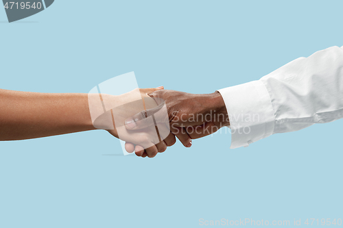 Image of Two male hands shaking isolated on blue studio background