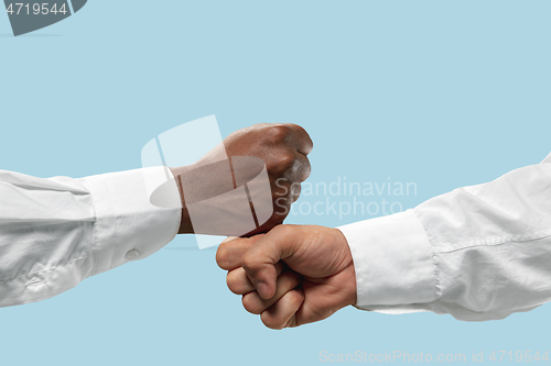 Image of Two male hands competion in arm wrestling isolated on blue studio background