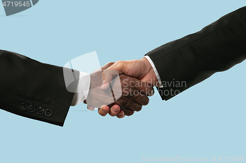 Image of Two male hands shaking isolated on blue studio background