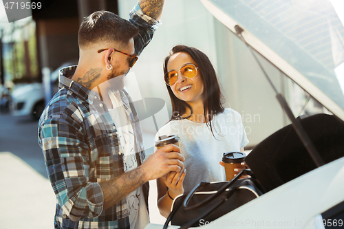 Image of Young couple preparing for vacation trip on the car in sunny day