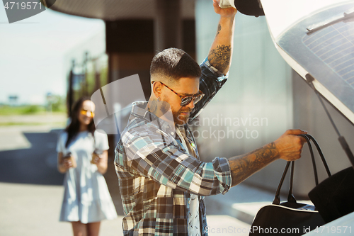 Image of Young couple preparing for vacation trip on the car in sunny day