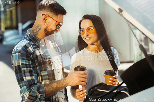 Image of Young couple preparing for vacation trip on the car in sunny day